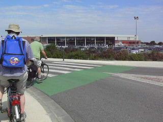 P1070589.JPG - Le marquage cyclable de traversée de chaussée est correct, mais les trottoirs subsistent et les vélos se retrouvent sur des trottoirs sans indication ni signalisation. De plus l'angle du virage est aigü et le croisement de cycles impossible.