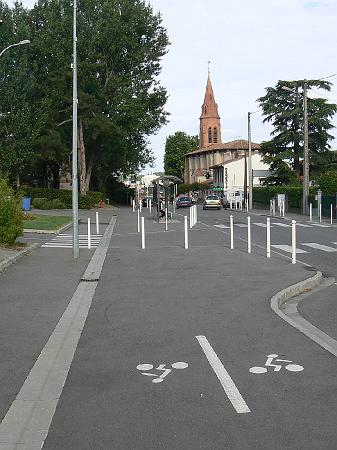 P1070557.JPG - Pour aller jusqu'à l'église : faut-il sortir de la piste au niveau du parking ou poursuivre sur le trottoir ? aucune indication sur la piste ni sur la chaussée.