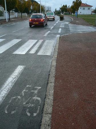 0810F218.jpg - Les bandes latérales alternent avec les passages protégés par des haies. Au niveau des intersection, la piste redevient une bande afin de ne pas contraindre les movements du cycliste. Le franchissement de la piste est matérialisé et la bande du stop est en retrait de la piste.